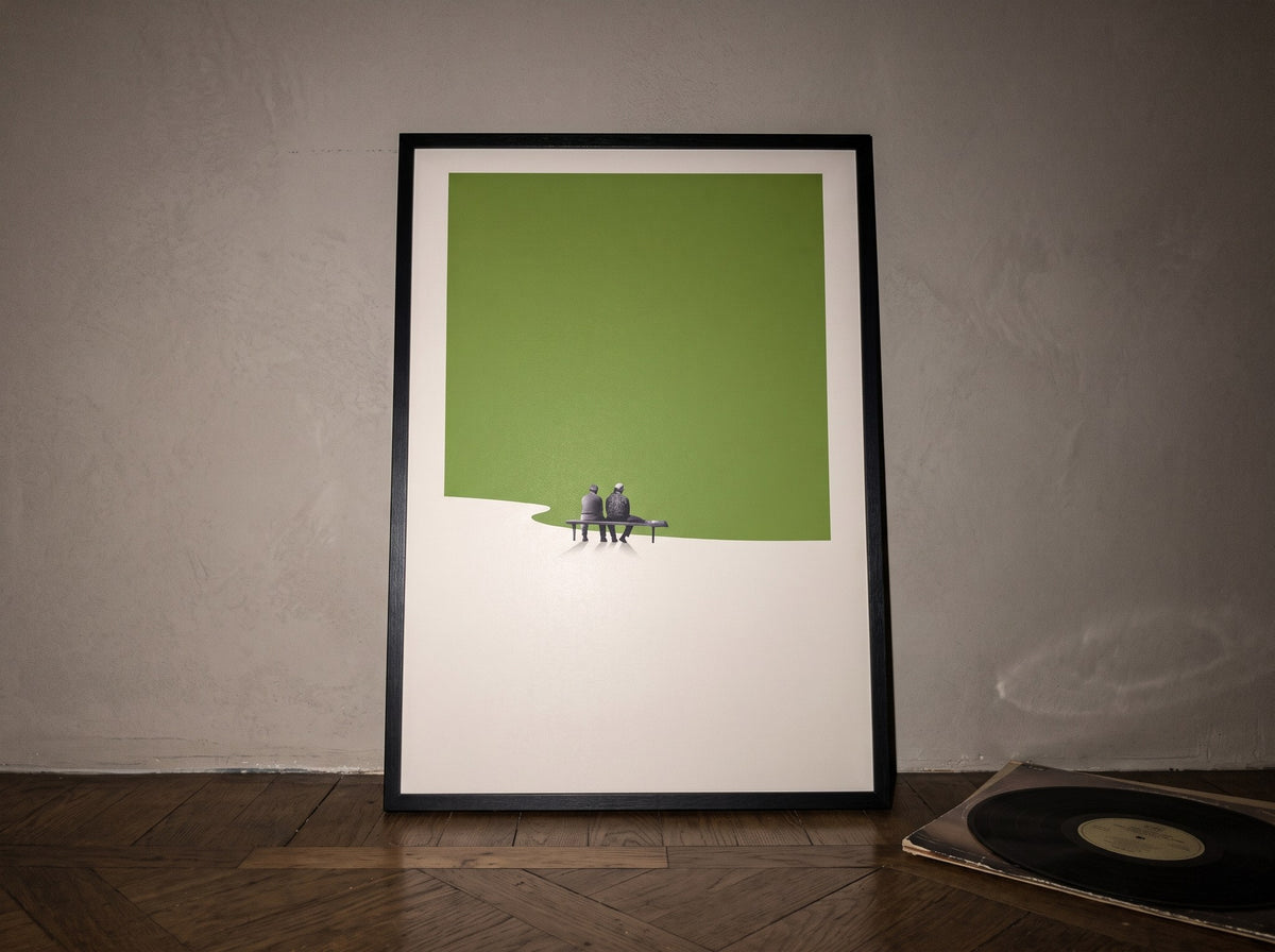 Yosun yeşili minimalist poster, ahşap parke üzerinde duvara yaslanmış siyah çerçeveli, eski bir plakla birlikte