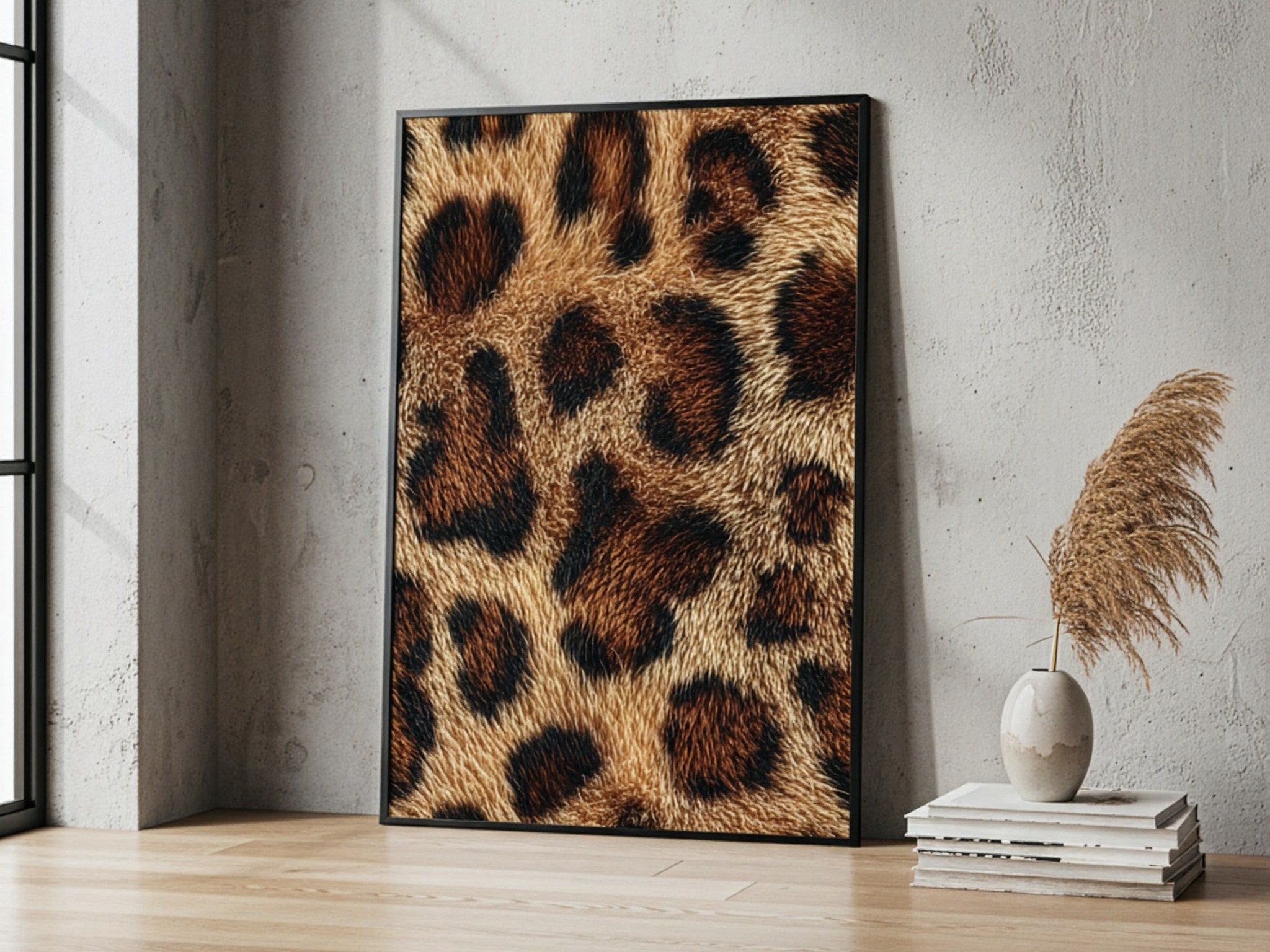 Leopar desenli poster, salon duvarına yaslanmış siyah çerçeveli, yanında pampas ve kitaplar